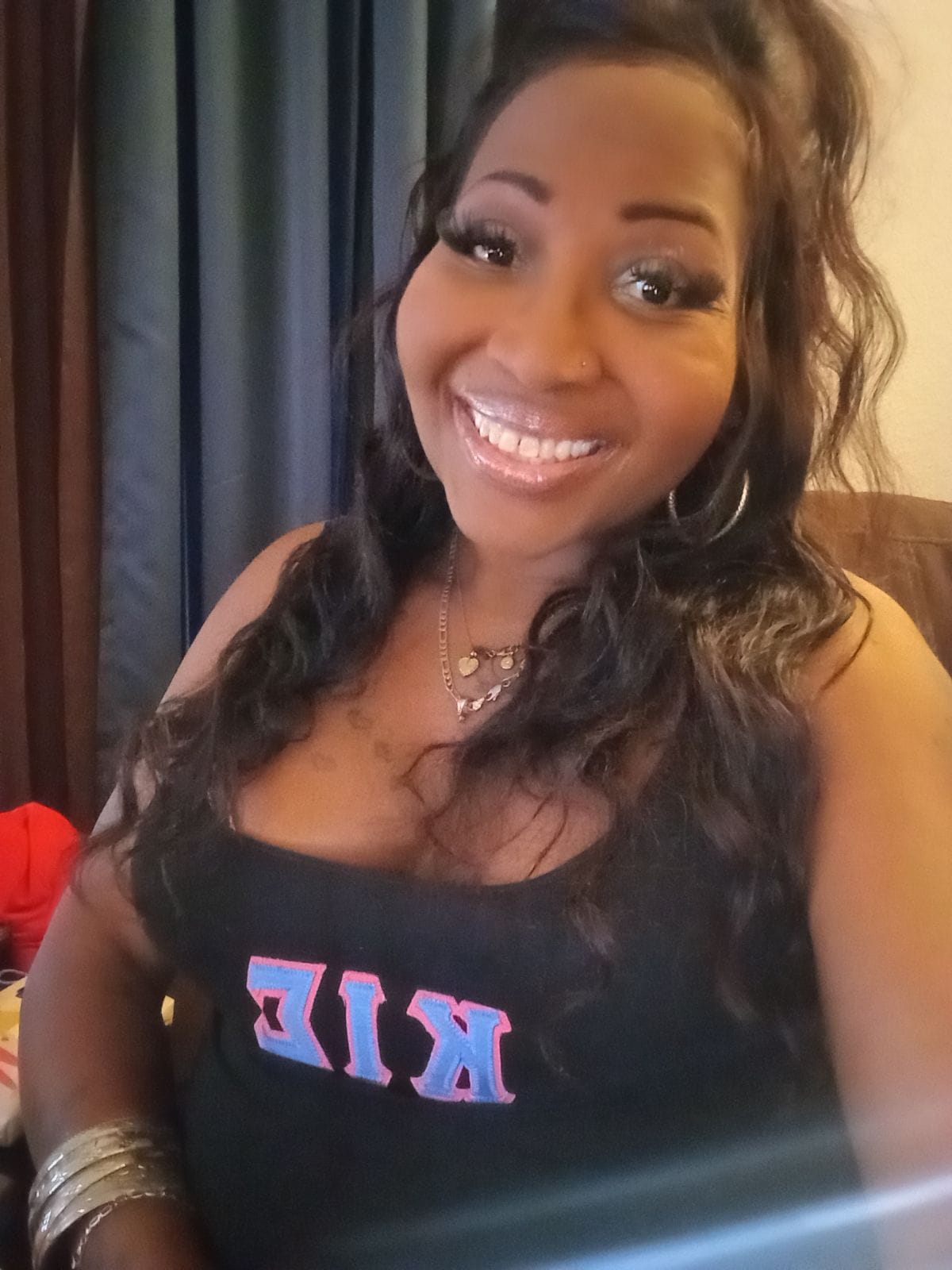 Kimberly Jordan, a smiling Black trans woman, wearing a black top, advocating for inclusivity in nonbinary shopping.