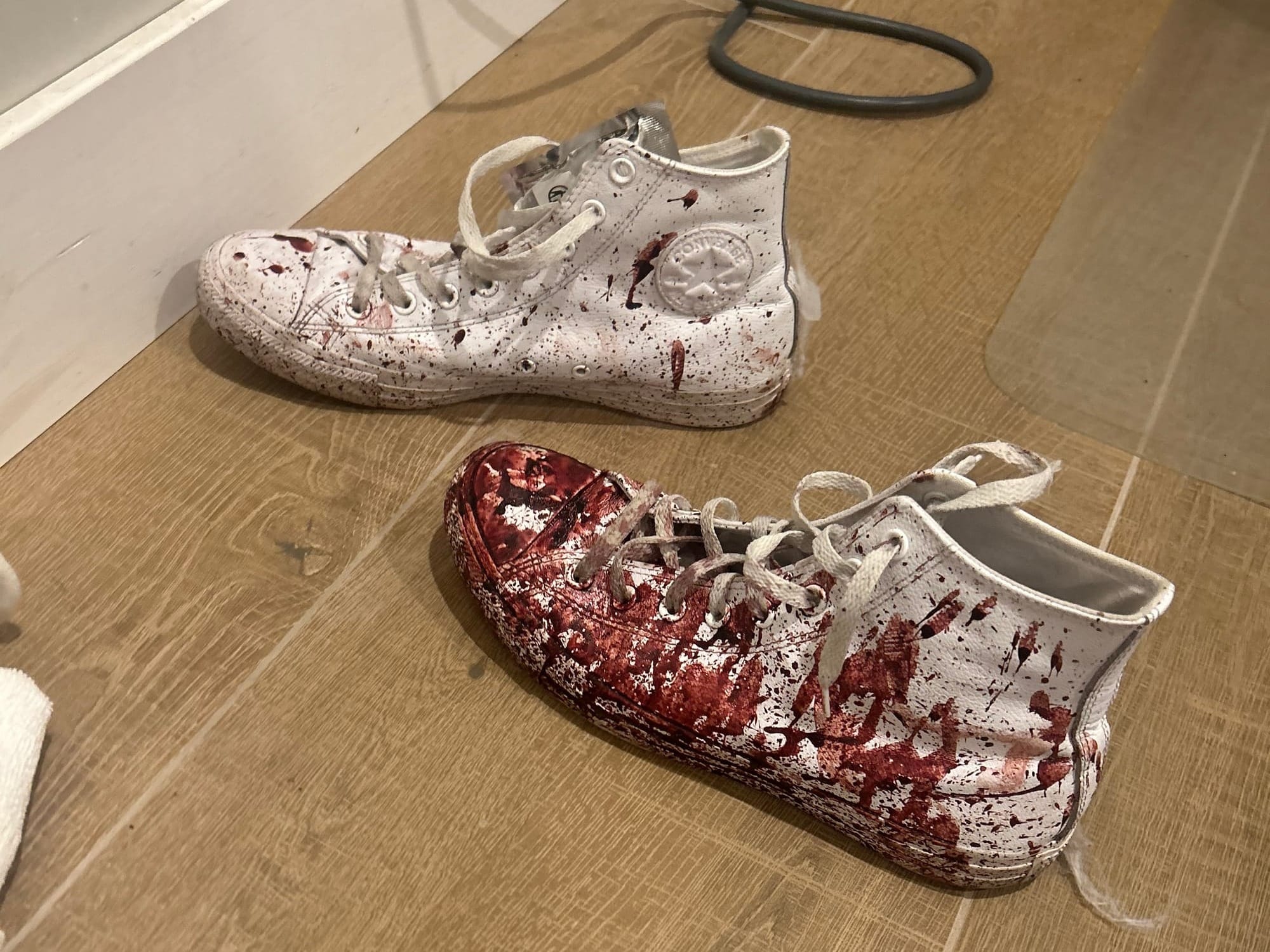 A pair of white converses covered in blood