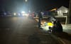 A person is lying on their back on the sidewalk with police officers shining a light and providing assistance