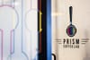 A close up image of a glass door, featuring the "Prism Coffee Lab" Logo.